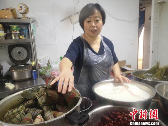 鄭春玲將兩張大粽葉窩成漏斗狀，填上糯米，放上兩粒紅棗，再加一片小粽葉，用棉線纏繞綁好，一個紅棗粽就成了，用時僅8秒?！「呖档?攝